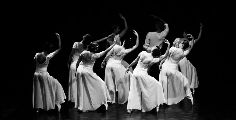 Foto preto e branco de nove bailarinas distribuidas no palco.