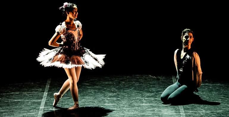 Foto de casal em apresentação, onde a bailarina está vestida com uma graciosa fantasia e o parceiro está de joelhos.